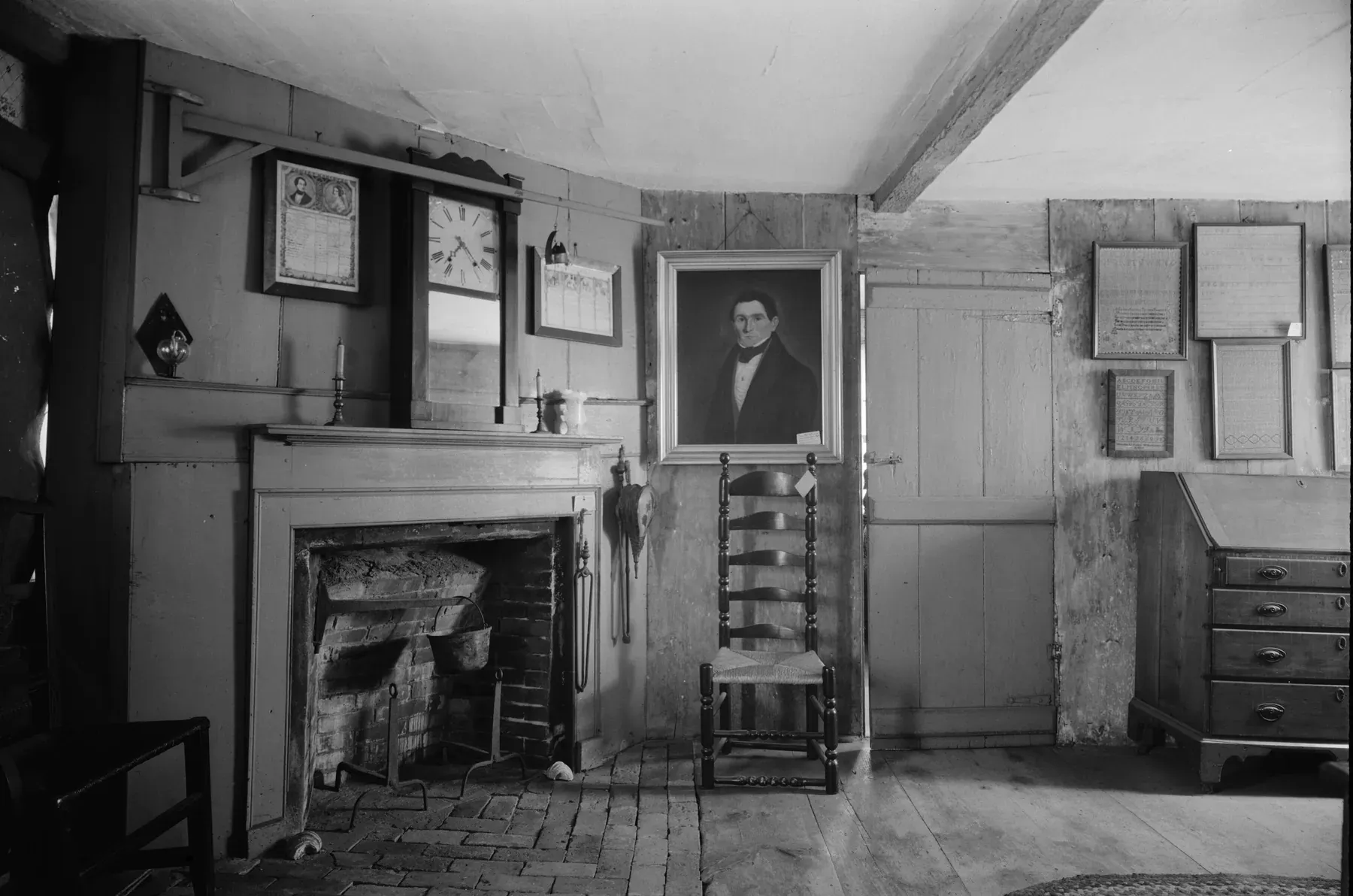 Parlor of the Fairbanks House with a brick hearth, a ladder-back chair, a slant-front desk and a wide plank floor