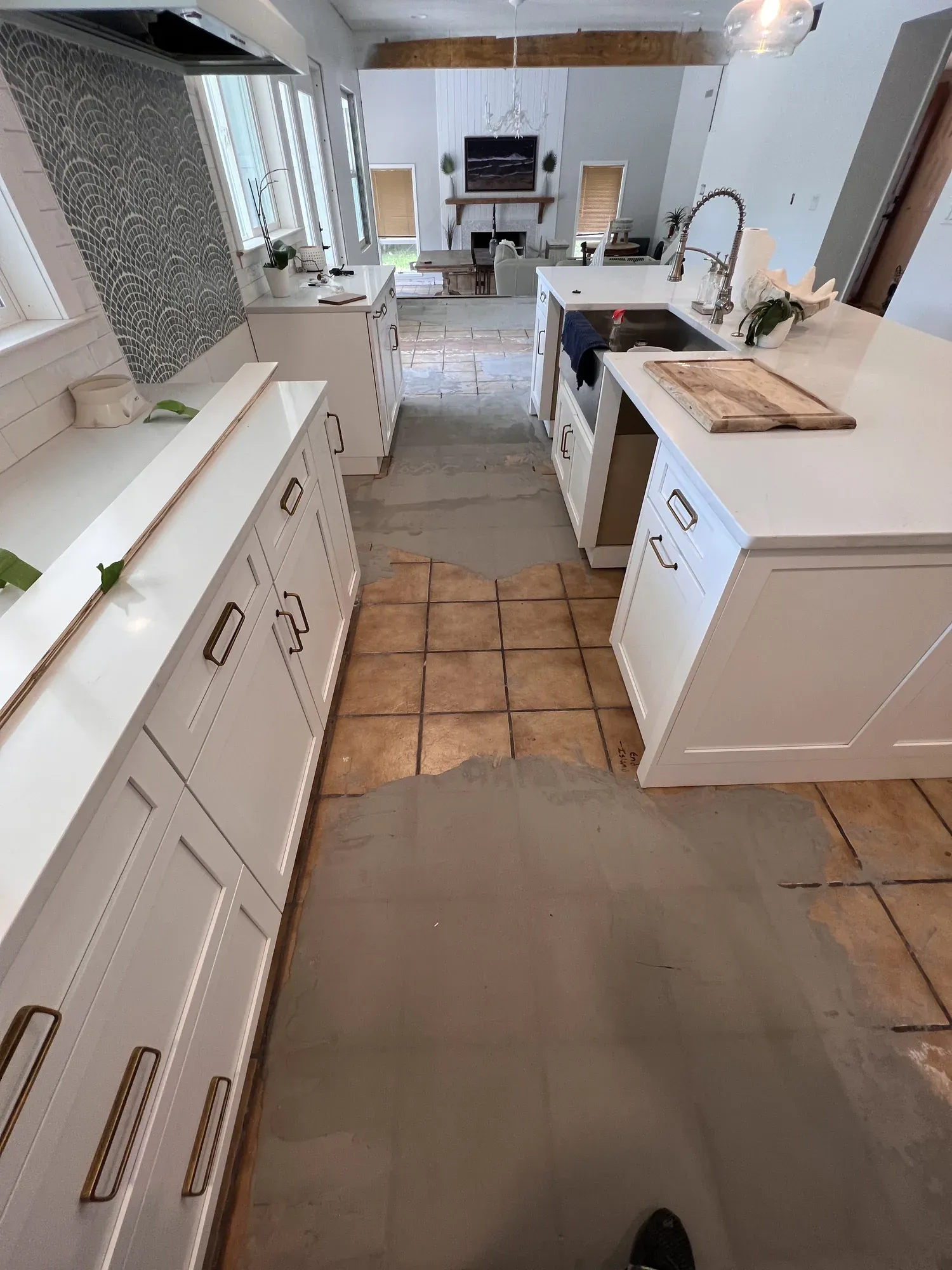 Kitchen with old terracotta tile partly removed and leveling compound spread over the exposed slab