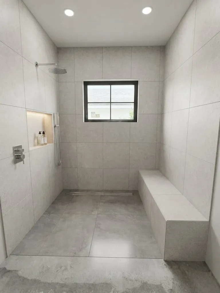 The same shower finished in large-format porcelain, with a lit niche, a tiled bench and a linear drain