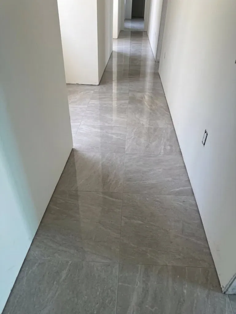 The same hallway finished in polished stone-look tile, with the joints running straight down the length of the run