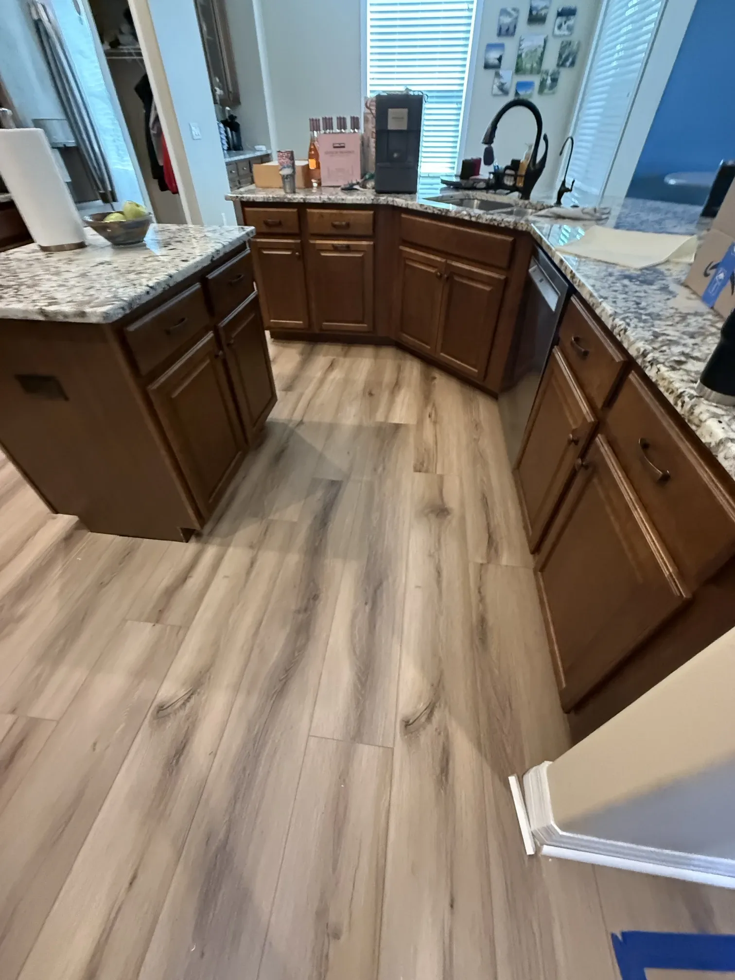 Kitchen with light wood-look vinyl plank newly installed between wood cabinets and a granite island